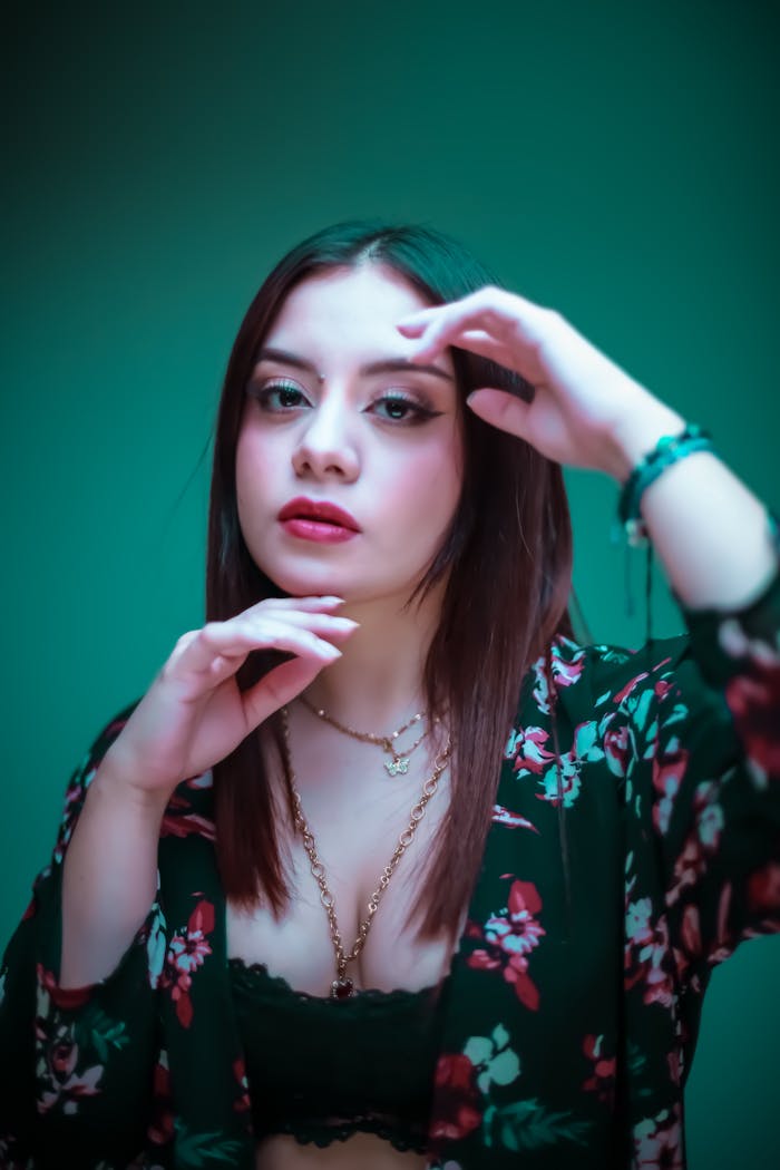 Captivating portrait of a woman in floral attire against a teal background.