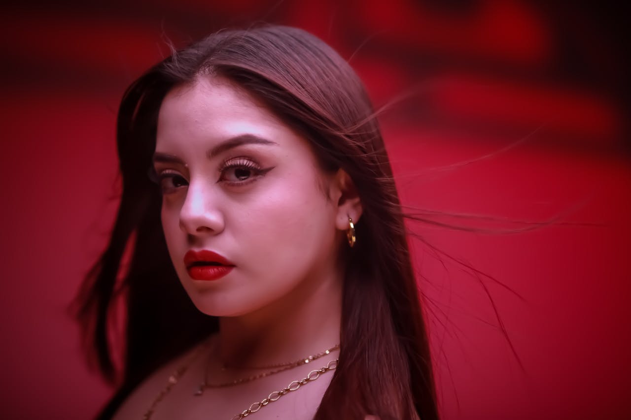 Portrait of a woman with bold red lips and vibrant background, exuding confidence.