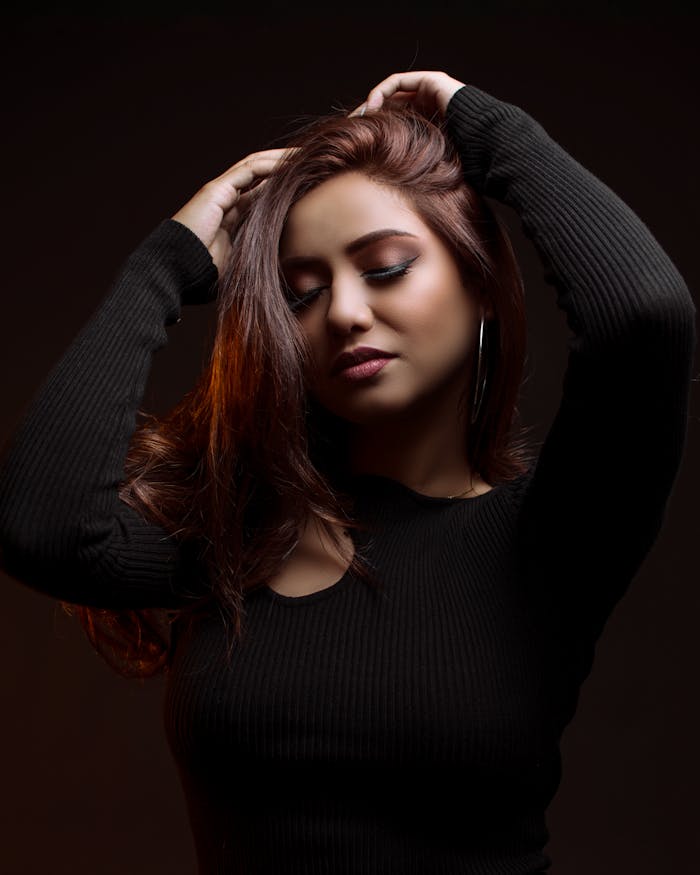 Striking portrait of a woman with closed eyes in a dark setting, exuding elegance.